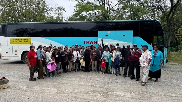 Group posing in front of a tour bus