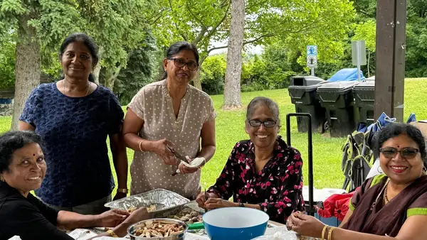 People serving food at a picnic table