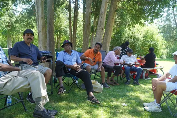People seated in lawn chairs under trees