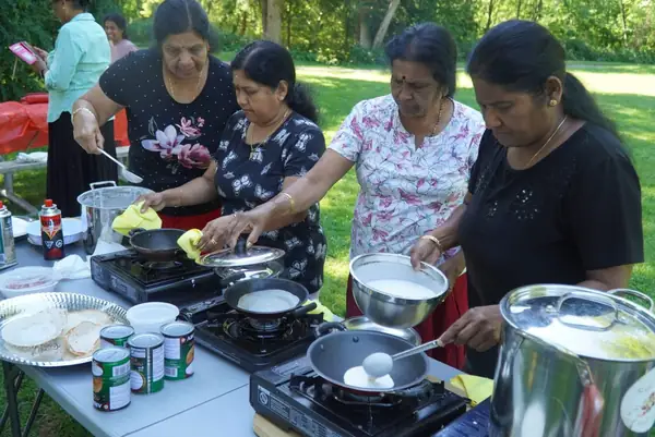 People cooking in large pots at an outdoor table