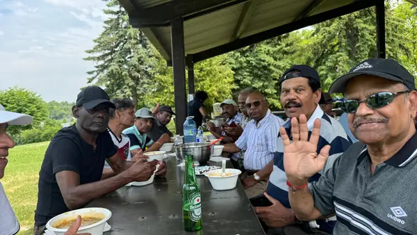 People sharing a meal at a picnic table under a pavilion