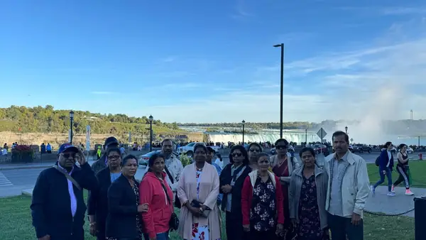 Large group posing outdoors under a blue sky