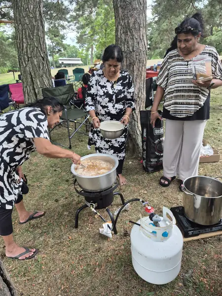 People cooking with large pots outdoors on the grass