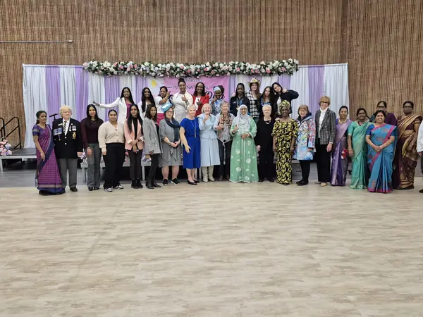 Large group posing in a hall in front of a decorated stage