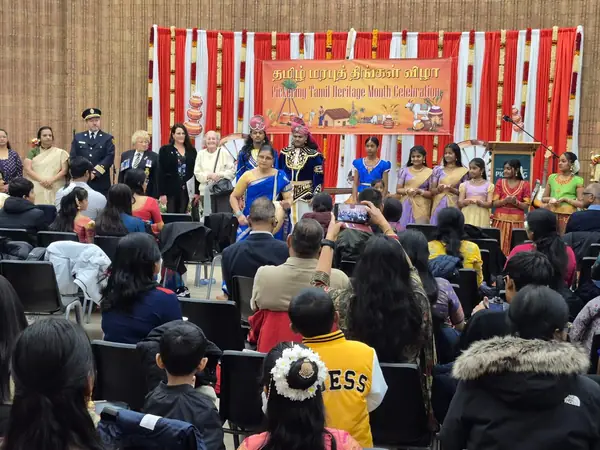 Audience seated in a hall facing a decorated stage