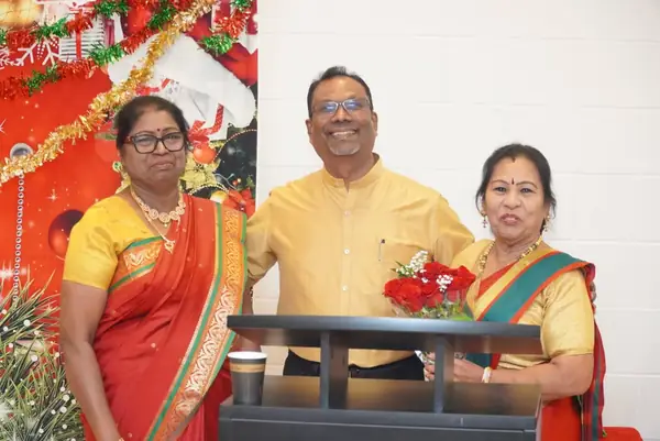 Three people standing at a podium decorated with flowers
