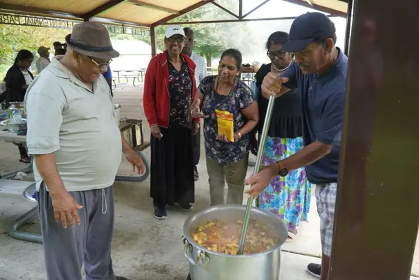 People cooking in a large pot outdoors