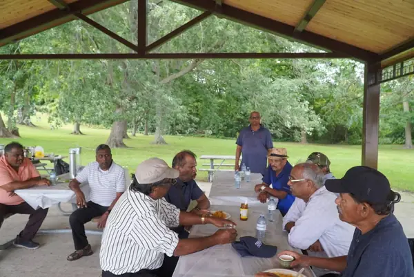 People seated at a picnic table under a pavilion