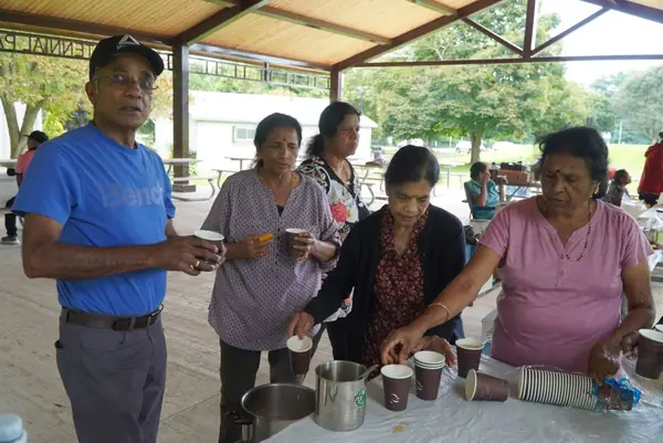 People serving food at a picnic table
